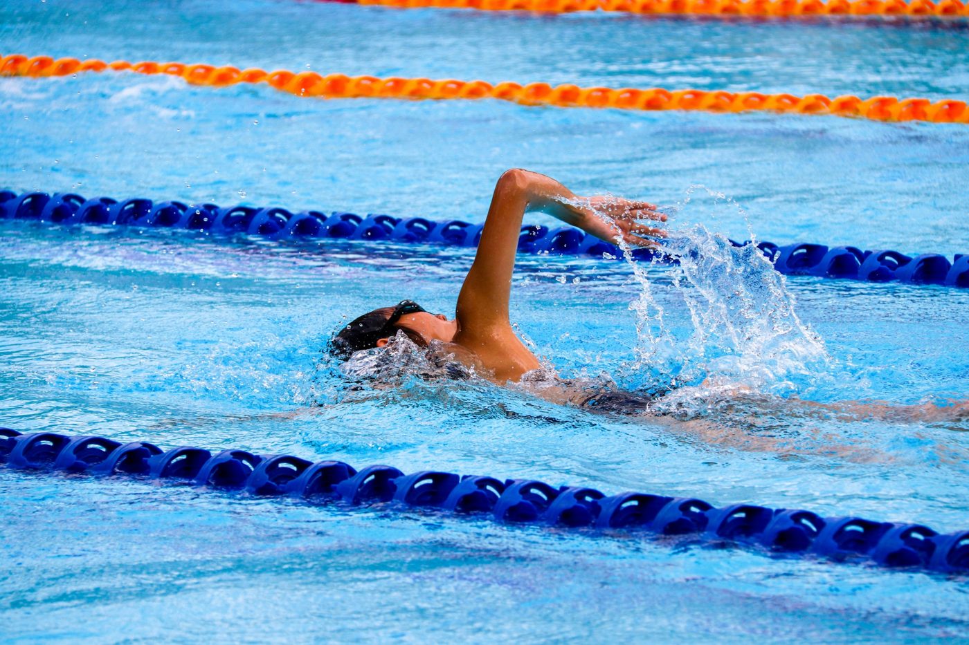 A swimmer racing freestyle between lane lines